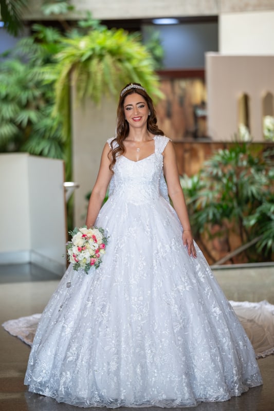 Noiva de corpo inteiro com o buquê, num jardim