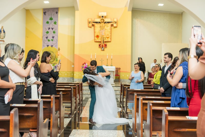 Igreja cheia: o noivo inclina a noiva num beijo entre os convidados