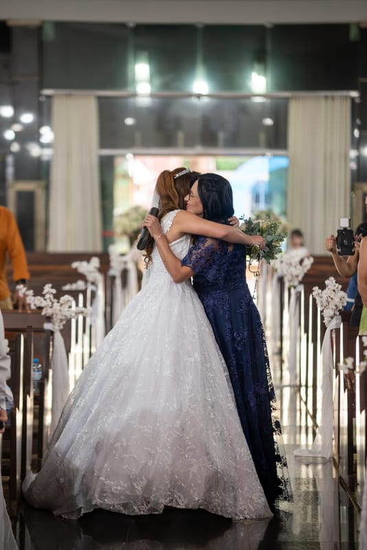 Noiva abraçando a mãe no corredor da igreja