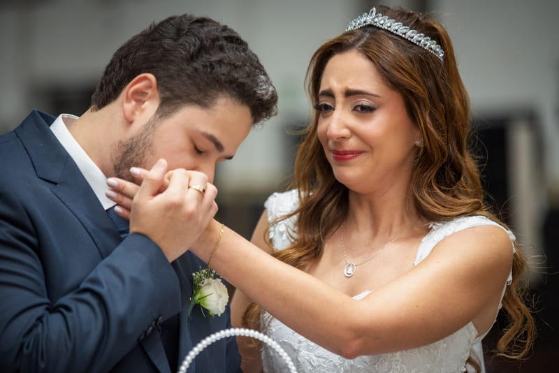 Noiva emocionada enquanto o noivo beija a mão dela
