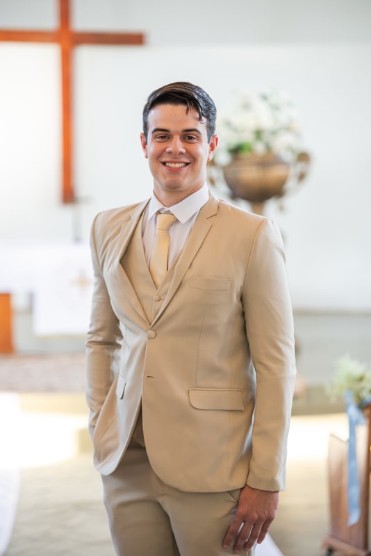 Noivo de terno claro sorrindo na igreja