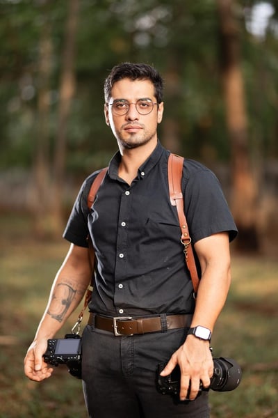 Lucas Mamede com duas câmeras, em pé num parque